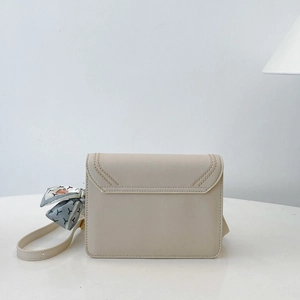 Close-up of beige flap crossbody bag with V-shaped stitching and silk scarf accent