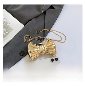 Detailed size comparison of a metallic gold bow shoulder bag with a smartphone