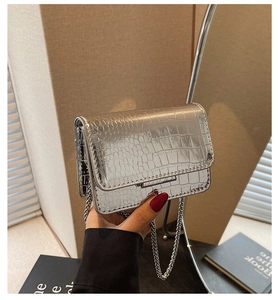 Detail of silver crocodile-embossed mini bag with metallic chain and flap closure