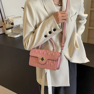 Detailed close-up of pink quilted leather bag featuring a black floral metal lock clasp