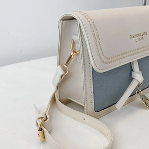 Close-up of contrast color crossbody bag with floral stitching and gold hardware detail