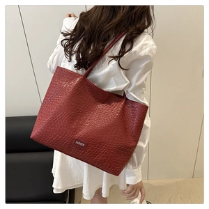 Detail of dark red tote bag with woven texture and a decorative fashion label