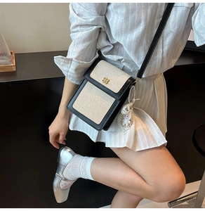 Close-up of canvas crossbody bag with metal petal clasp and plush doll pendant