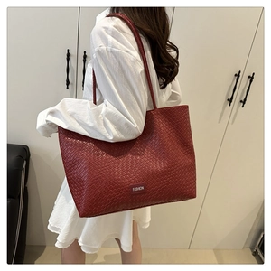 Detail of red woven texture tote bag with Fashion lettering on model shoulder