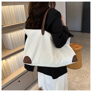 Bolso de viaje blanco grande con asas de cuero marrón llevado por una mujer joven