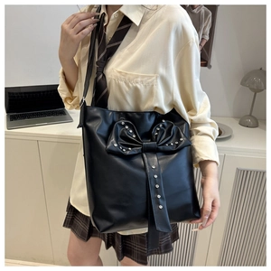 Close-up of black PU leather shoulder bag with decorative bow and sparkling rhinestones
