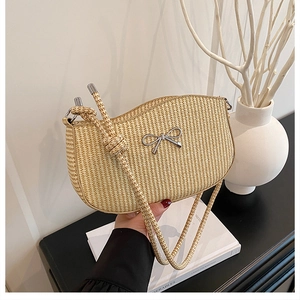 Detail showing natural straw weave texture and silver metal bow on a summer shoulder bag
