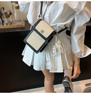 Detail of cream canvas mini crossbody bag with black leather trim and pearl charm