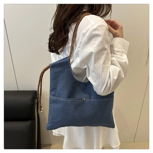 Detail of denim tote bag with brown woven rope handle and secure metal button snap