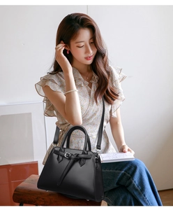 Detail of black lychee grain leather handbag with decorative buckle and metal studs