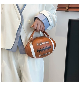 Fashionable rugby-shaped handbag with white stripes and chain strap held by a model