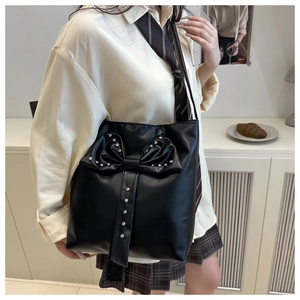 Close-up of black PU leather shoulder bag featuring a large bow with silver rhinestone details