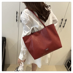 Detail of red PU woven leather tote bag featuring a black Fashion logo tag and texture