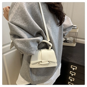 Macro detail of the white lychee grain leather texture and round handle on the mini bag