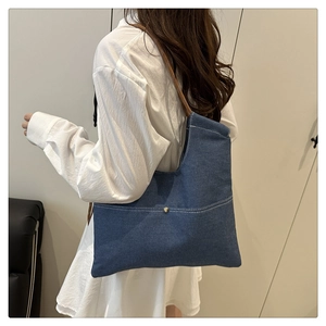 Detail of blue denim tote bag with contrast stitching and patterned woven shoulder strap