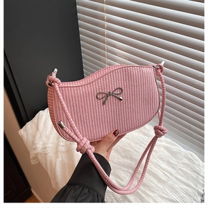 Close-up of pink woven texture and silver bow detail on minimalist shoulder bag