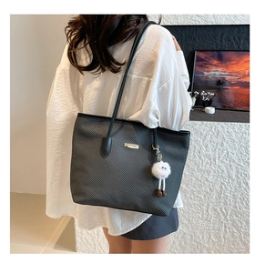 Detail of black tote bag featuring diagonal scratch-resistant texture and plush charm
