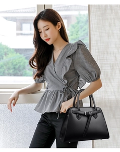 Detail of black leather handbag with pebble grain texture and decorative buckle