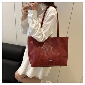 Close-up of red woven texture tote bag with dual shoulder straps and fashion label detail