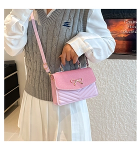 Close-up of pink and lavender patchwork crossbody bag with gold bow on a stylish model
