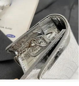 Macro detail of silver croc-effect leather texture with metallic chain and stitching