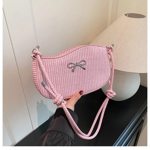 Detail of pink woven shoulder bag featuring a silver bow accent and rope texture