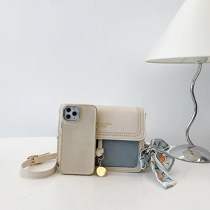 Detail view of contrast color crossbody bag with silk scarf and gold plaque ornament