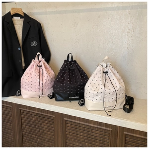Detail of drawstring bags in black pink and white with embossed bow texture and logo