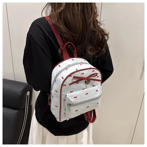 Detailed back view of a mini white backpack with red bows and silver heart charm