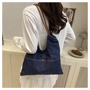 Detail view of large denim tote bag with rope handles and metal button accent