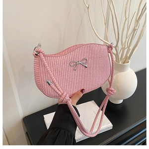 Detailed macro shot of pink woven bag featuring a silver bow accent and thick knotted strap