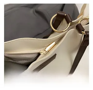 Close-up of golden circular metal hardware and brown leather handles on white tote bag