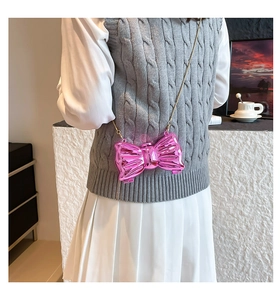 Close-up of metallic pink bow-knot crossbody bag with elegant gold chain strap