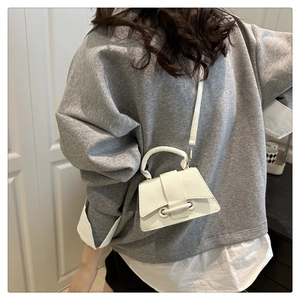 Close-up of white litchi grain leather crossbody bag with metallic buckle detail
