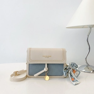 Detail view of contrast color crossbody bag with silk scarf and gold lettering