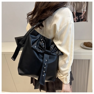 Detail of black leather tote bag featuring a large bow with silver rivets and studs