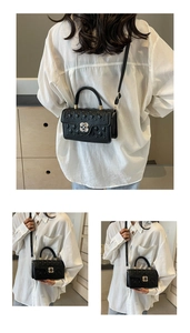 Detail of black quilted crossbody bag featuring unique flower-shaped metal lock and dual straps