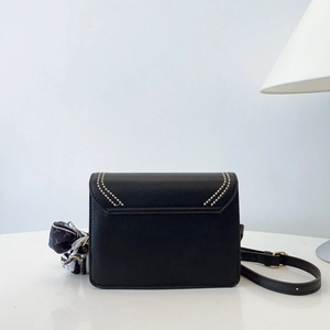 Close-up of black crossbody square bag with metal bead trim and decorative silk scarf