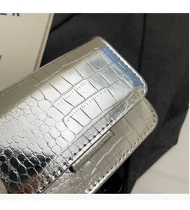 Close-up of silver crocodile pattern patent leather with detailed stitching on mini bag