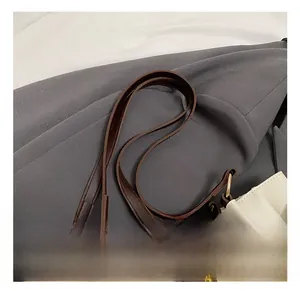 Close-up of comfortable cream leather shoulder straps with brown trim and metal buckles