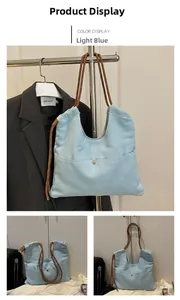 Detail of light blue denim tote bag with brown rope handles and golden snap button closure