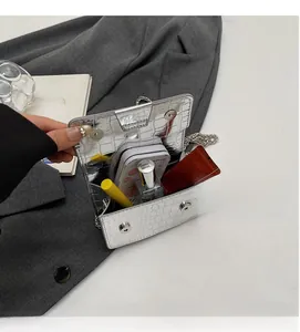 Detail of silver crocodile-patterned mini bag showing dual magnetic closure and interior space