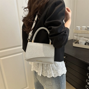 Borsa a mano con paillettes argento con manico curvo e tracolla indossata da una modella
