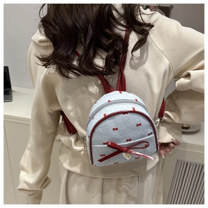 Detailed back view of a mini blue polka dot backpack with red bows and heart pendant