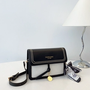 Detail of black and white leather crossbody bag with silk scarf and gold pendant