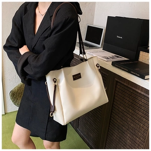 Detail of minimalist cream tote bag with contrast dark brown straps in professional setting