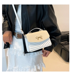 Detail of crossbody bag featuring woven texture flap and golden bow metal buckle
