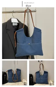 Detail of blue denim tote bag featuring brown rope handles and white contrast stitching