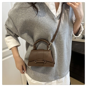 Detail of a dark brown pebble leather mini crossbody bag styled on a gray sweater