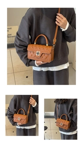 Macro shot of brown quilted leather bag featuring a clover-shaped twist lock closure
